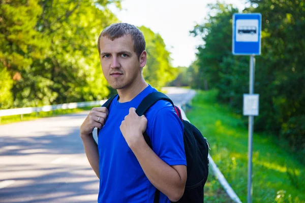 Hombre caminante con pie de mochila en parada de autobús en camino forestal —  Fotos de Stock