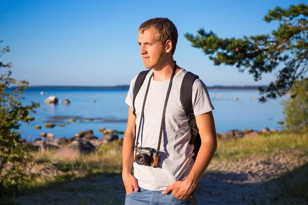 Homme avec sac à dos et rétro caméra sur la plage — Photo