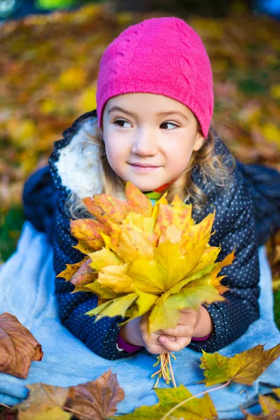 Dziewczynka z bukietem liści klonu leżące w parku jesień — Zdjęcie stockowe