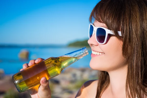 Porträtt av vacker kvinna dricker öl på stranden — Stockfoto