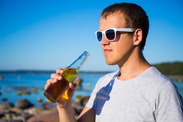 Handsome man drinking beer on the beach — Stock Photo, Image