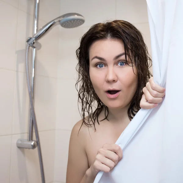 Beautiful shocked woman covering her body with curtain in shower — Stock Photo, Image