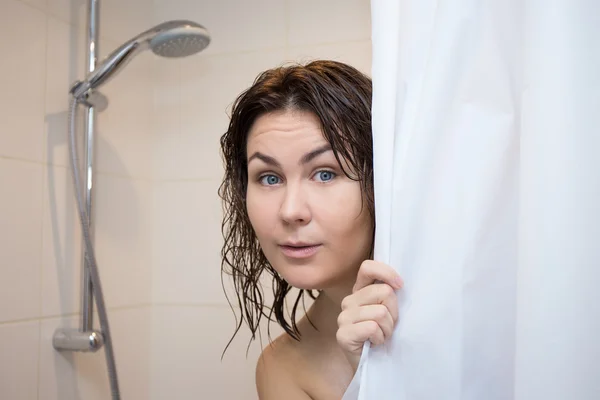 Cute scared woman hiding behind shower curtain — Photo