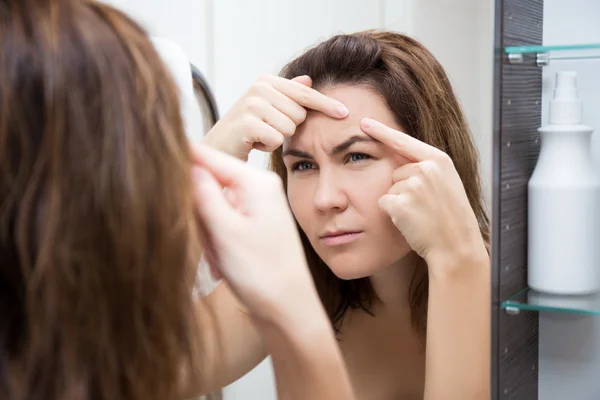 Concepto de problema piel - mujer triste mirando en el espejo —  Fotos de Stock