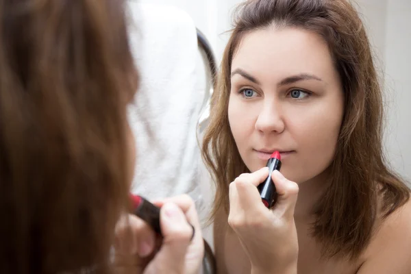 Primer plano de mujer mirando en el espejo y la aplicación de lápiz labial — Foto de Stock