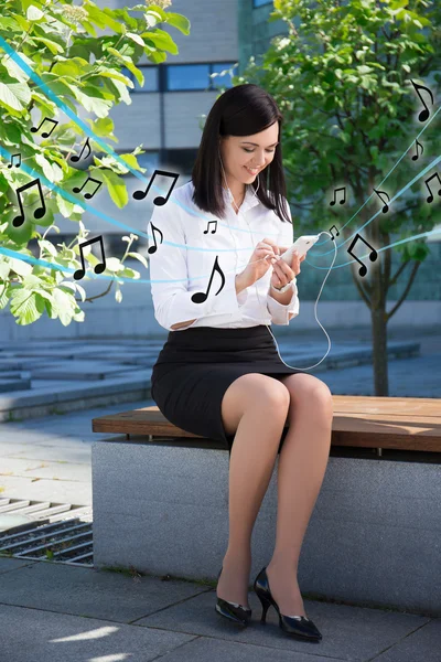 Business woman lyssnar musik med smart telefon i stadsparken — Stockfoto