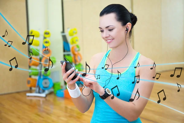 Vacker smal kvinna lyssnar musik i gymmet — Stockfoto