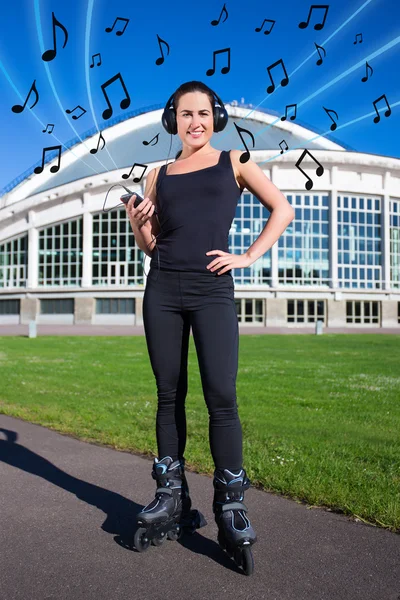 Щаслива молода жінка в роликових ковзанах слухає музику в парку — стокове фото