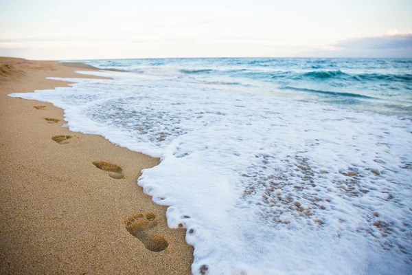 Следы на песчаный пляж и море волны — стоковое фото