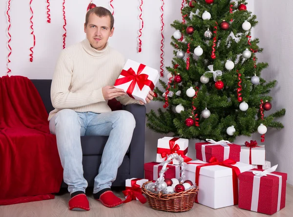 Ung man sitter i inrett vardagsrum med julgran — Stockfoto