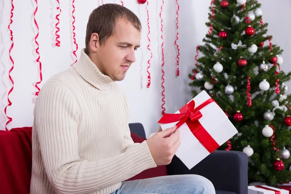 Christmas concept - happy young handsome man opening gift in liv — Stock Photo, Image