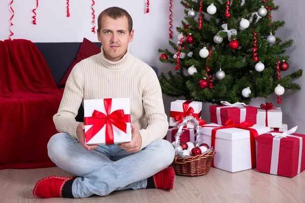 Jeune homme avec boîtes présents de Noël sous le sapin de Noël — Photo