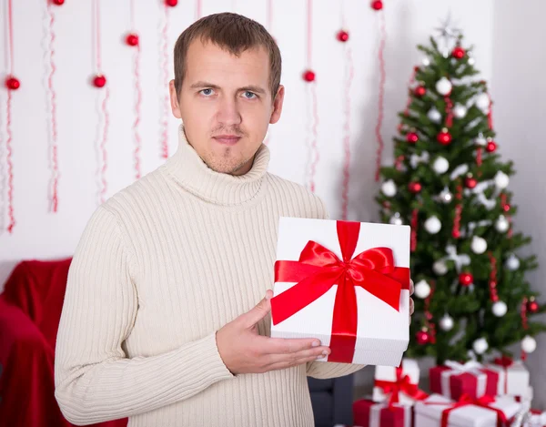 Joven sosteniendo la caja presente de Navidad en decorado — Foto de Stock