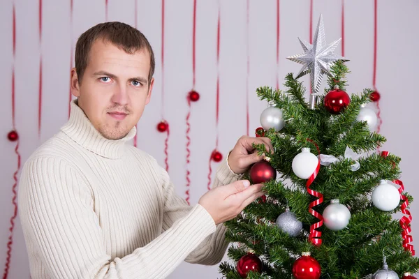 Happy handsome man decorating Christmas tree — Stok Foto