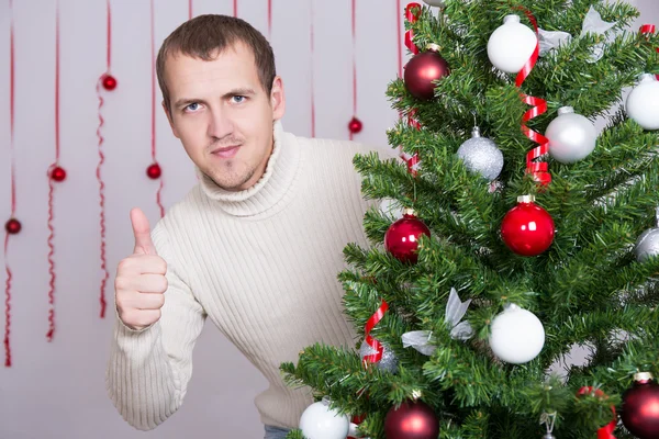 Ritratto dell'uomo bello pollici in alto e decorato albero di Natale — Foto Stock