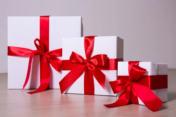 White gift boxes with red ribbon on wooden background Royalty Free Stock Photos