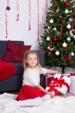 Noel ağacı ile dekore edilmiş oturma odasında oturan küçük kız