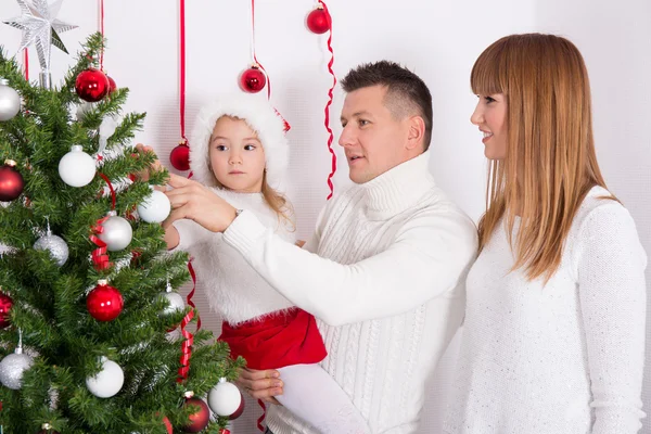 Happy parents and daughter decorating Christmas tree Stock Image