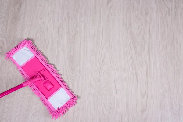 Limpeza esfregão de conceito - rosa no chão de madeira — Fotografia de Stock