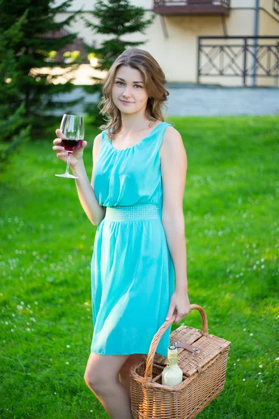 Щаслива красива жінка з кошиком для пікніка п'є вино в парку — стокове фото