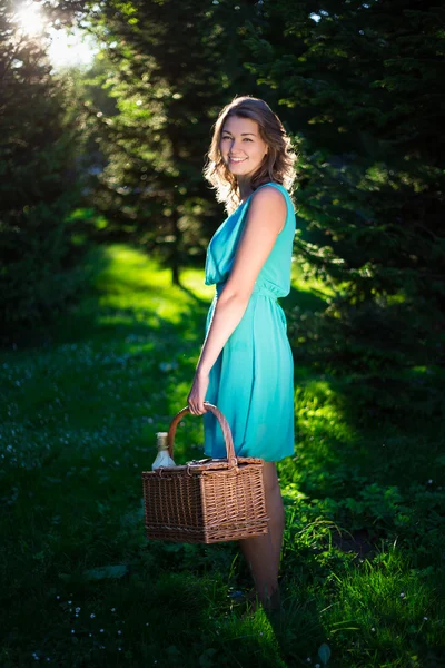 Jovem mulher bonita com cesta de piquenique e garrafa de vinho em mi — Fotografia de Stock