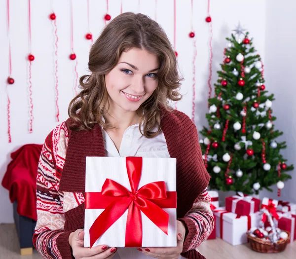 Jovem mulher segurando a caixa de presente de Natal no quarto decorado — Fotografia de Stock