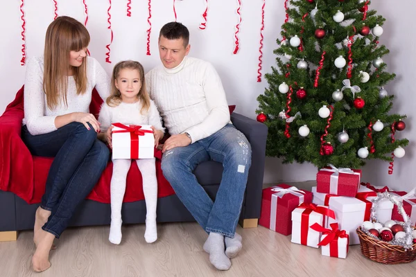 Lycklig familj sitter i inrett vardagsrum med jul tre — Stockfoto