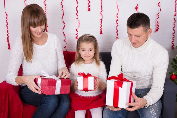 Glad familj sitter på soffan och öppna julklappar — Stockfoto