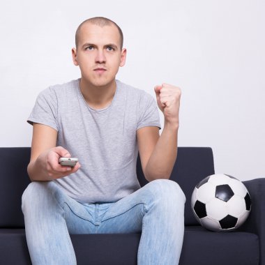 topu ile kanepede oturan ve evde tv izlerken adam futbol fan