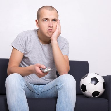 Televizyonda futbol maç izlerken topu ile sıkılmış fan