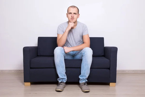 Handsome man sitting on sofa at home — Stock Photo, Image