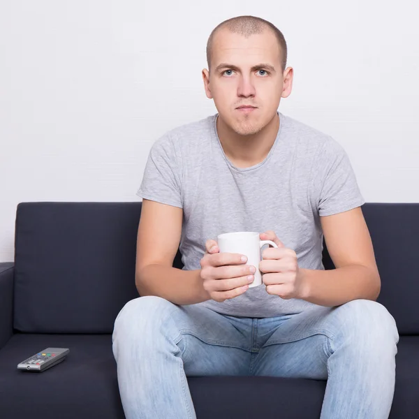 Schöner Mann auf Sofa sitzen und Fernsehen mit Tasse Tee — Stockfoto