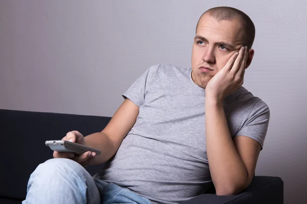 Bored man sitting on sofa and watching movie or tv — Stock Photo, Image