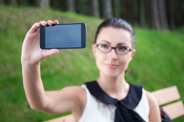Vacker flicka visar smart telefon med blank skärm — Stockfoto