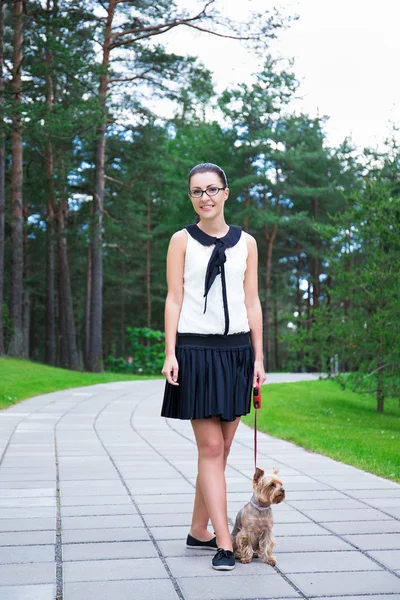 Szczęśliwa dziewczyna spaceruje z pies yorkshire terrier w parku — Zdjęcie stockowe