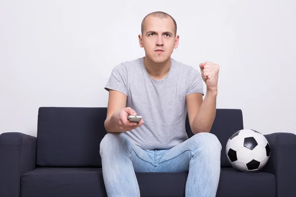 Fan piłki nożnej człowiek z piłkę, oglądanie tv w domu — Zdjęcie stockowe