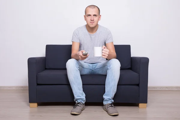 Przystojny mężczyzna oglądanie telewizji z filiżanką herbaty — Zdjęcie stockowe