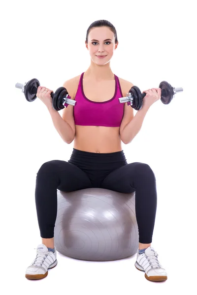 Jeune femme en vêtements de sport assis sur ballon de fitness avec haltères — Photo