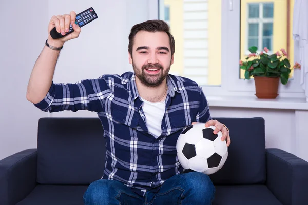 自宅のテレビでサッカーを見て幸せな若い男 — ストック写真