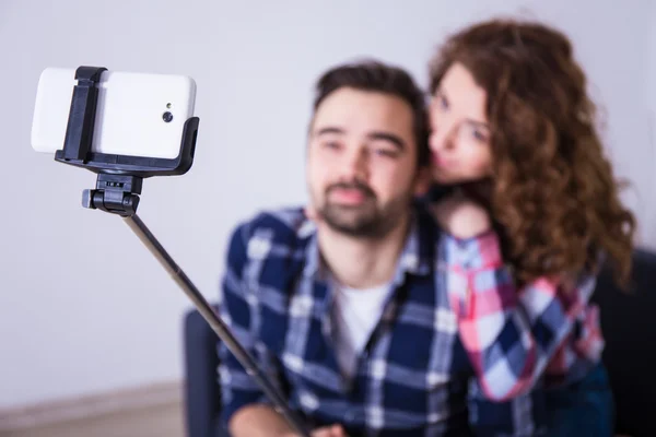 Jovem casal tirando foto com telefone inteligente na vara de selfie — Fotografia de Stock