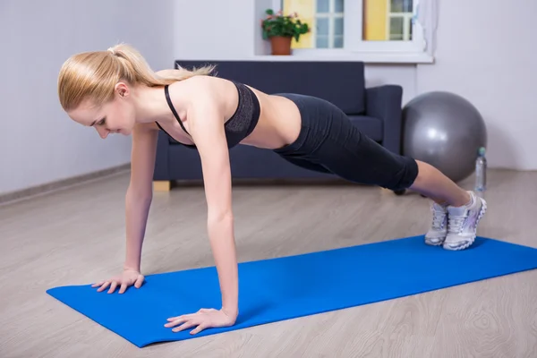 Mladá krásná žena, která dělá push up cvičení doma — Stock fotografie