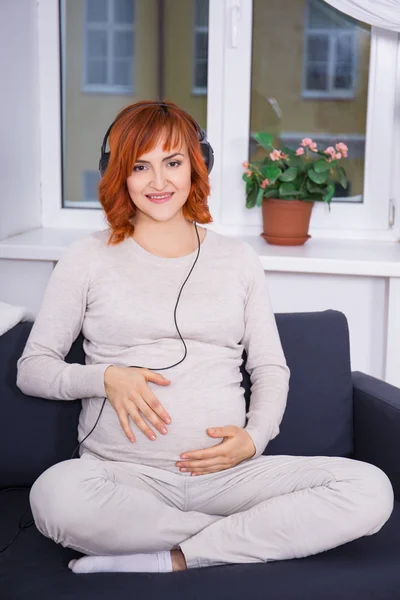 Mladá těhotná žena poslech hudby doma — Stock fotografie