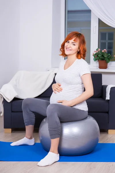 Szczęśliwa kobieta w ciąży ćwiczenia na fitball w domu — Zdjęcie stockowe