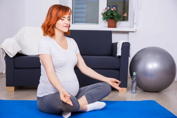 Mujer bonita embarazada haciendo yoga en casa —  Fotos de Stock