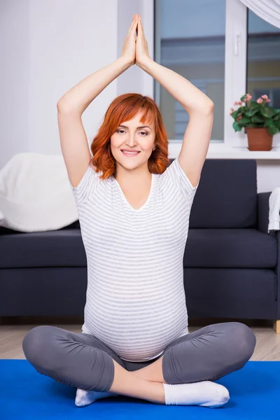 Vackra gravid kvinna gör yoga hemma — Stockfoto