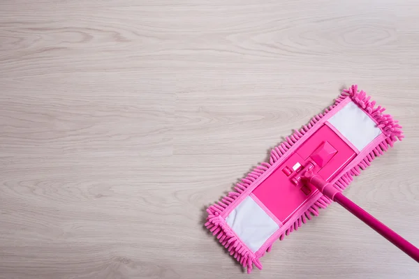 Cerca de la fregona del piso color rosa sobre fondo de madera — Foto de Stock