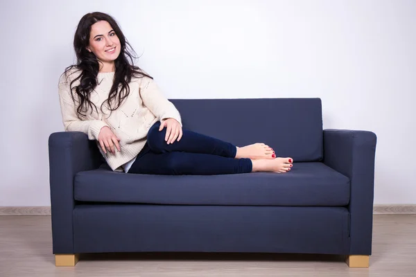 Porträtt av ung kvinna sitter på soffan hemma — Stockfoto