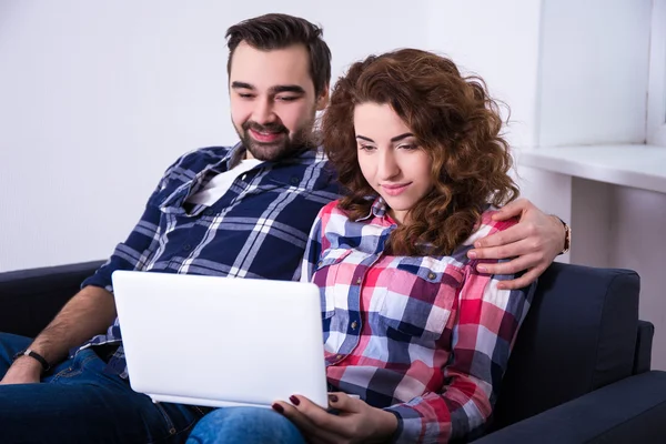 Glada unga par med laptop på soffa — Stockfoto