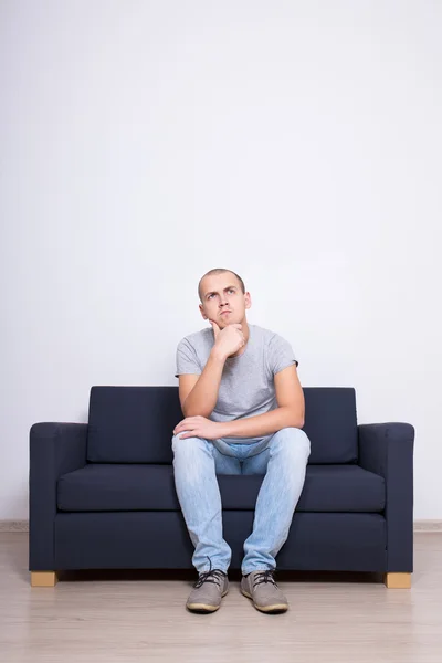 Idea concept - dreaming man sittin on sofa over white wall — Stock Photo, Image