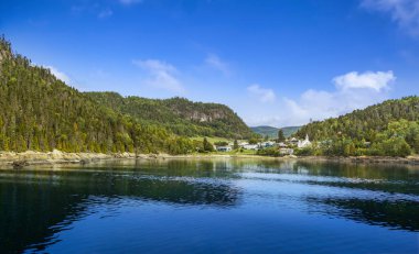 Kanada fiyortundaki limandan dağların arasındaki küçük köye bak.